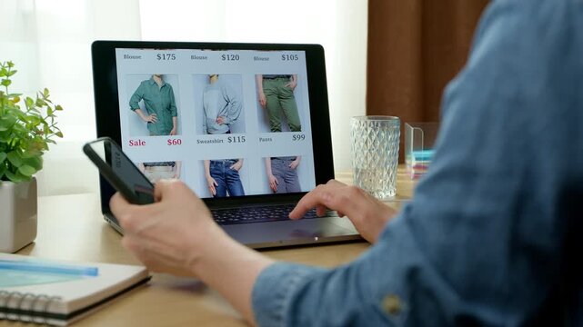Online shopping using a laptop and phone. E-commerce. A woman chooses clothes through an online store.