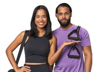 Young Latino couple ready for gym training showing a copy space on a palm and holding another hand on waist.