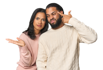 Young Latino couple in studio holding and showing a product on hand.