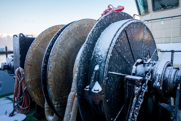  Close up anchor and towing winch on  tug boat. Winch with towing rope covered with snow