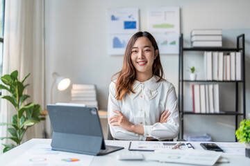 Young asian businesswoman sitting with arms crossed at office desk