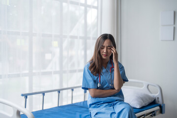 Young doctor experiencing burnout sitting on empty bed in hospital room