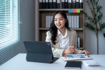 Businesswoman is using a tablet for a video conference and analyzing financial graphs