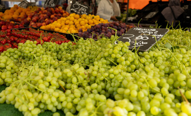 Close up white grapes, tomatoes and plums and other fruits in the background. Healthy food, ripe, ready to eat, market stall, trader, food. Rotterdam weekly market.