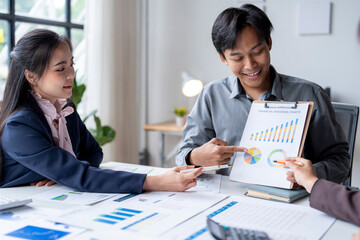 Asian businesspeople analyzing financial business charts using calculator and laptop computer