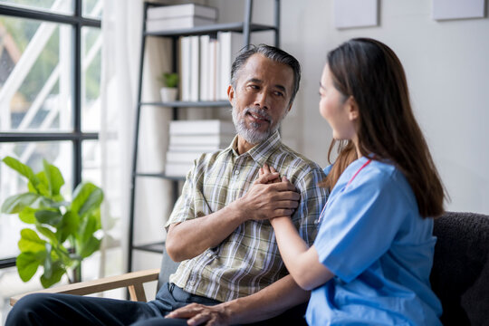 Nurse comforting senior man sitting on sofa at home