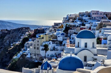 A stunning view of Santorini's iconic whitewashed buildings with blue domes overlooking the sparkling Aegean Sea, capturing the island's traditional Cycladic architecture and coastal beauty.