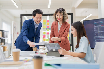 Fototapeta premium Creative Asian professionals brainstorming in a modern office. Business team collaborating on innovative ideas and strategies in a contemporary workspace, emphasizing teamwork and dynamic thinking