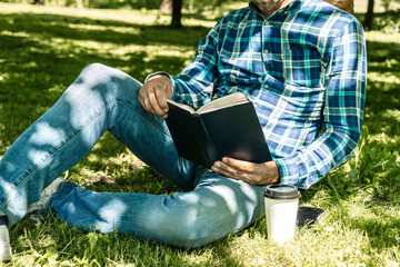 Fototapeta premium Reading a book. A young man reads a book or a textbook. Education, leisure, business concept.