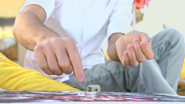 Man playing board game outdoors, he throws dice and makes move with chip, hands close-up.