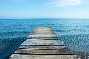 Fototapeta premium The end of a wooden pier that stretches out into the calm, blue waters of the ocean, epitomizing peace and summertime tranquility.