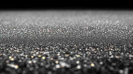 Fine silver glitter sparkles on a dark background, reflecting light and creating a mesmerizing, glowing effect