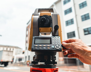land surveying total station instrument on a tripod with a building in the background