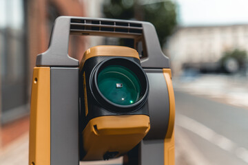 land surveying total station instrument on a tripod with a building in the background close up