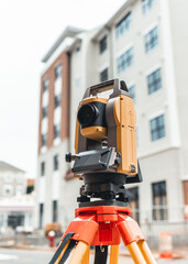 land surveying total station instrument on a tripod with a building in the background