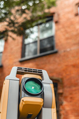 land surveying total station instrument on a tripod with a building in the background