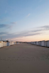 Peaceful Evening Beach with Endless Row of Beach Huts under Serene Sky at Sunset