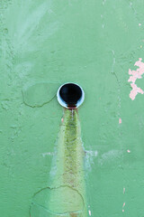 A sewer on the green concrete wall