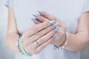 Female hand with long nails and a lilac and green nude nail polish