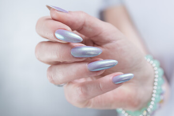 Female hand with long nails and a lilac and green nude nail polish