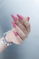 Woman hand with long nails manicure and light pink nail polish