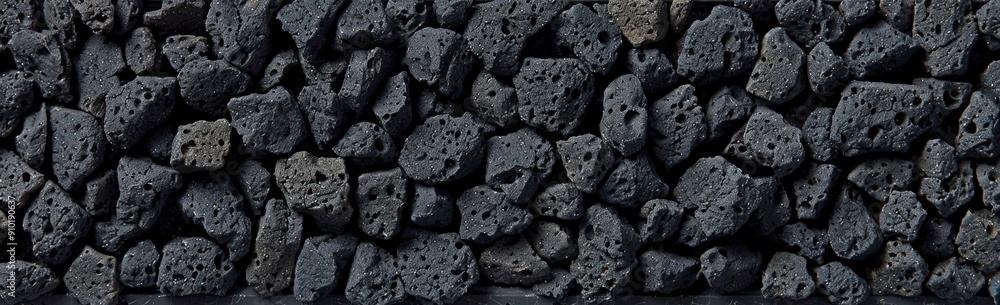 Poster volcanic rocks are stacked neatly, showcasing their rugged texture and dark coloration in a natural 