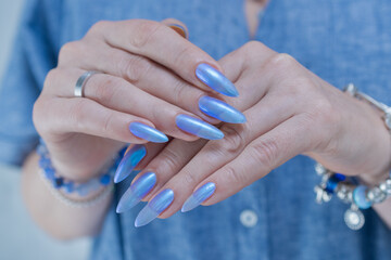 Woman's beautiful hand with long nails and light baby blue manicure	