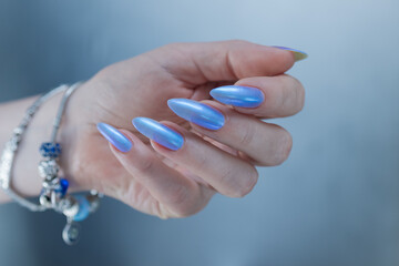 Woman's beautiful hand with long nails and light baby blue manicure	