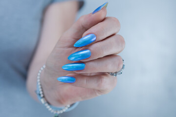 Woman's beautiful hand with long nails and light baby blue manicure	