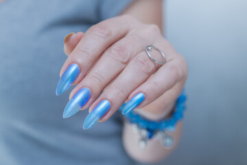Woman's beautiful hand with long nails and light baby blue manicure	