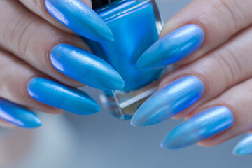 Female hand with long nails and bright light blue and silver manicure	