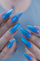 Female hand with long nails and bright light blue and silver manicure	