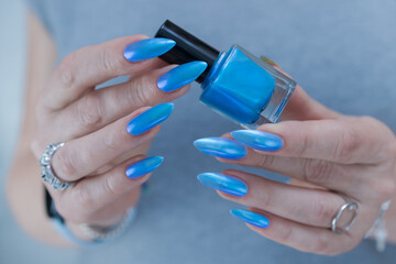 Female hand with long nails and bright light blue and silver manicure	