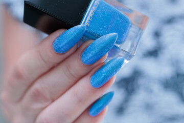Woman's beautiful hand with long nails and light baby blue manicure	