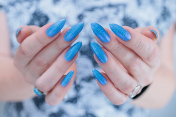 Woman's beautiful hand with long nails and light baby blue manicure	