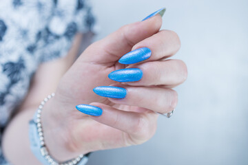 Woman's beautiful hand with long nails and light baby blue manicure	