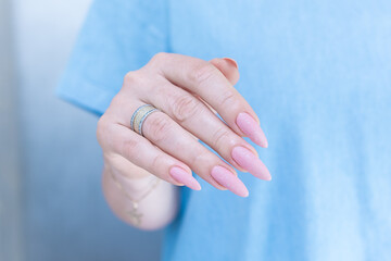 Woman's hands with long nails and a light pink color nail polish