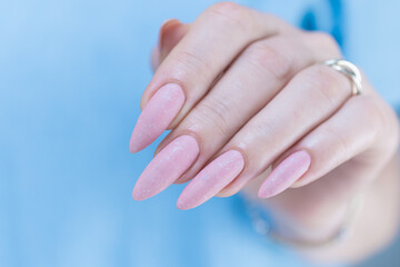 Woman's hands with long nails and a light pink color nail polish