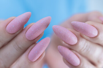 Woman's hands with long nails and a light pink color nail polish