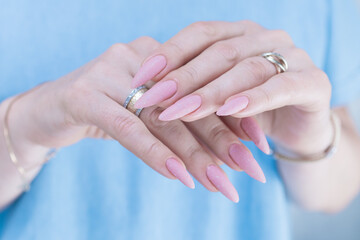 Woman's hands with long nails and a light pink color nail polish