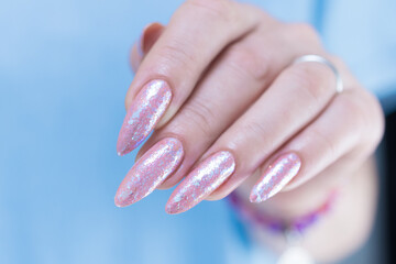 Woman's hands with long nails and a light pink color nail polish