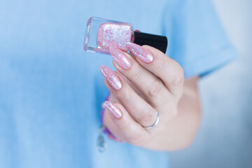 Woman's hands with long nails and a light pink color nail polish