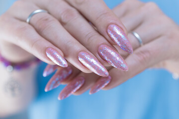 Woman's hands with long nails and a light pink color nail polish