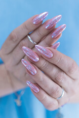 Woman's hands with long nails and a light pink color nail polish