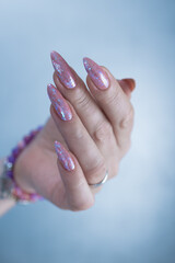Woman's hands with long nails and a light pink color nail polish