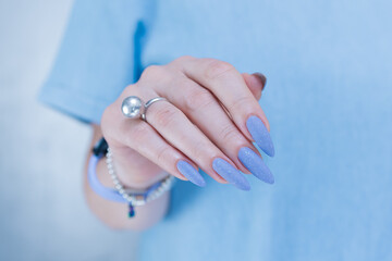 Woman's beautiful hand with long nails and light baby blue manicure	