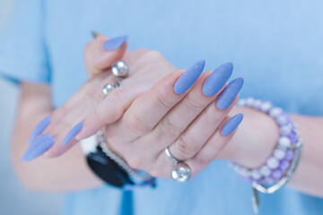 Woman's beautiful hand with long nails and matt light blue manicure	