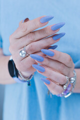 Woman's beautiful hand with long nails and light baby blue manicure	