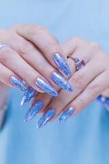 Woman's beautiful hand with long nails and bright blue manicure