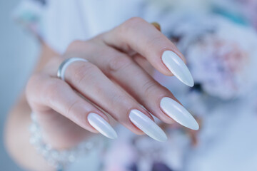 Woman's hands with long nails and a light white color nail polish